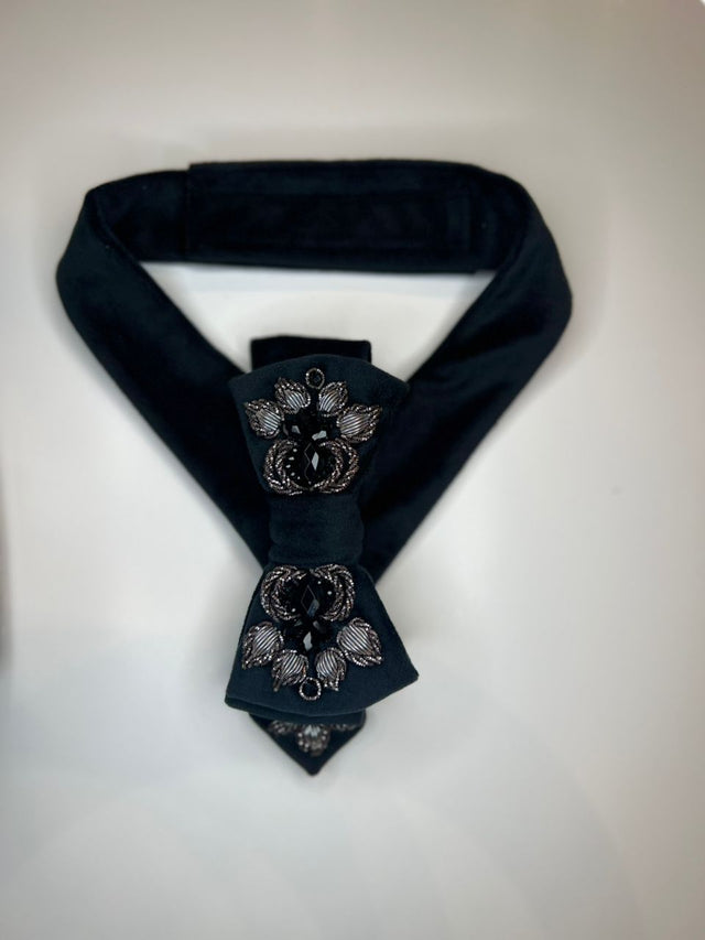 A dark navy blue velvet necktie with ornate silver and black crystal embellishments on the bow, displayed on a light gray background.