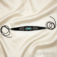 Black velvet Zinat choker necklace with silver and turquoise floral embroidery, laid flat with long cord ties on cream satin fabric.