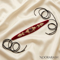 Red velvet Zinat choker necklace with gold floral embroidery and a central brown gemstone, laid flat with long cord ties on cream satin fabric.