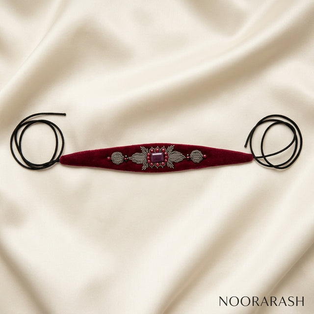 Burgundy velvet Zinat choker necklace with silver and pink crystal embellishments, laid flat with long cord ties on draped cream satin fabric.
